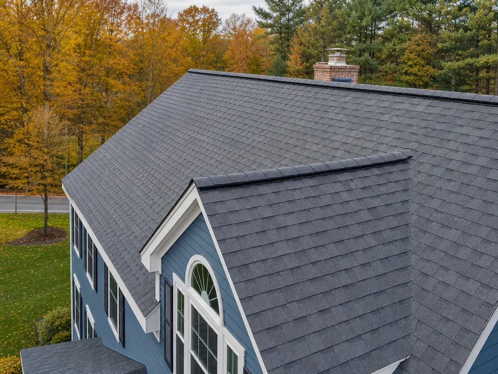 Completed asphalt shingle roof on a New England home with clean ridge lines and a ridge vent